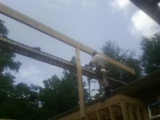 Carpenter setting a ridge beam over a new addition frame — Ice Dam Removal by Roofing Brothers in Haskell