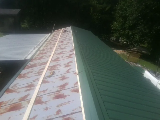 Old rusted panels beside newly installed green metal roofing — Wind Damage Roof Repair by Roofing Brothers in Haskell