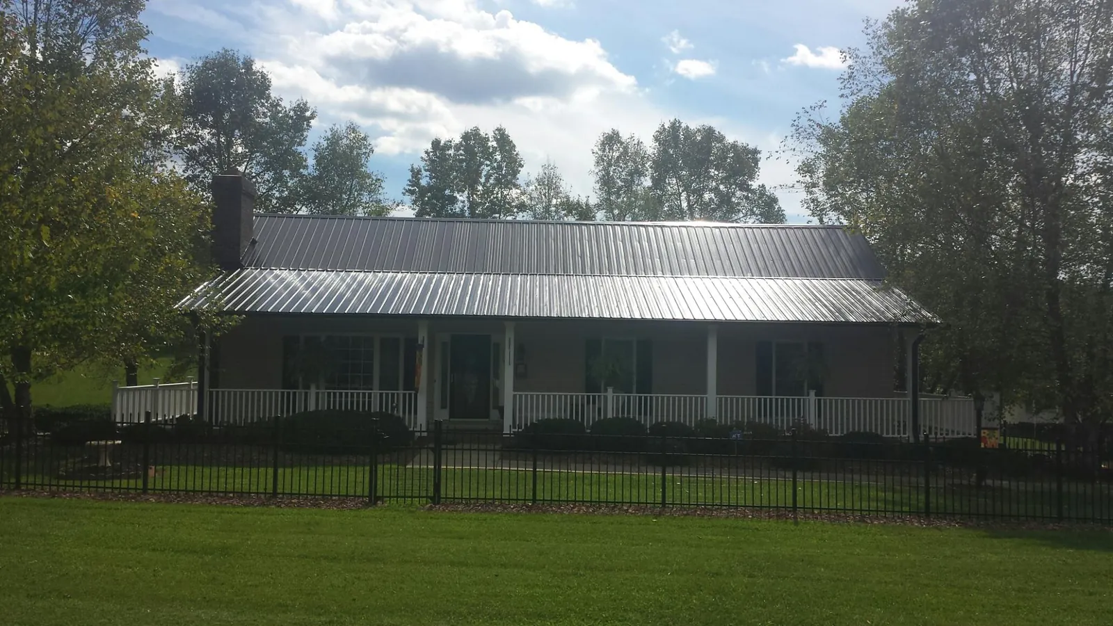 Gray metal roof on a brick ranch with a full width front porch — Gutter Guard Installation work by our crew in Haskell