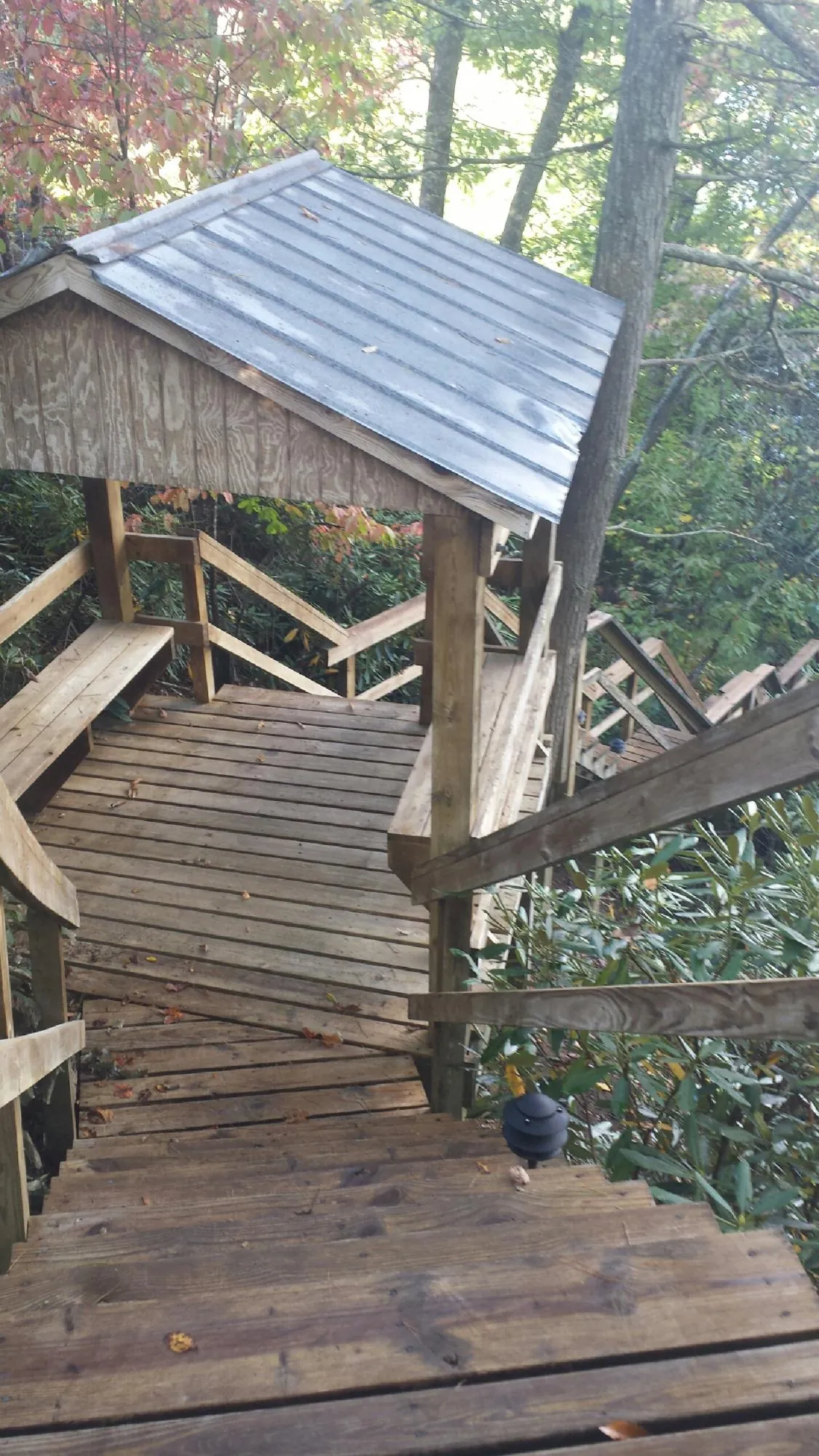 Metal roofed shelter over wooden steps on a wooded walkway — Skylight Repair & Installation work by our crew in Haskell