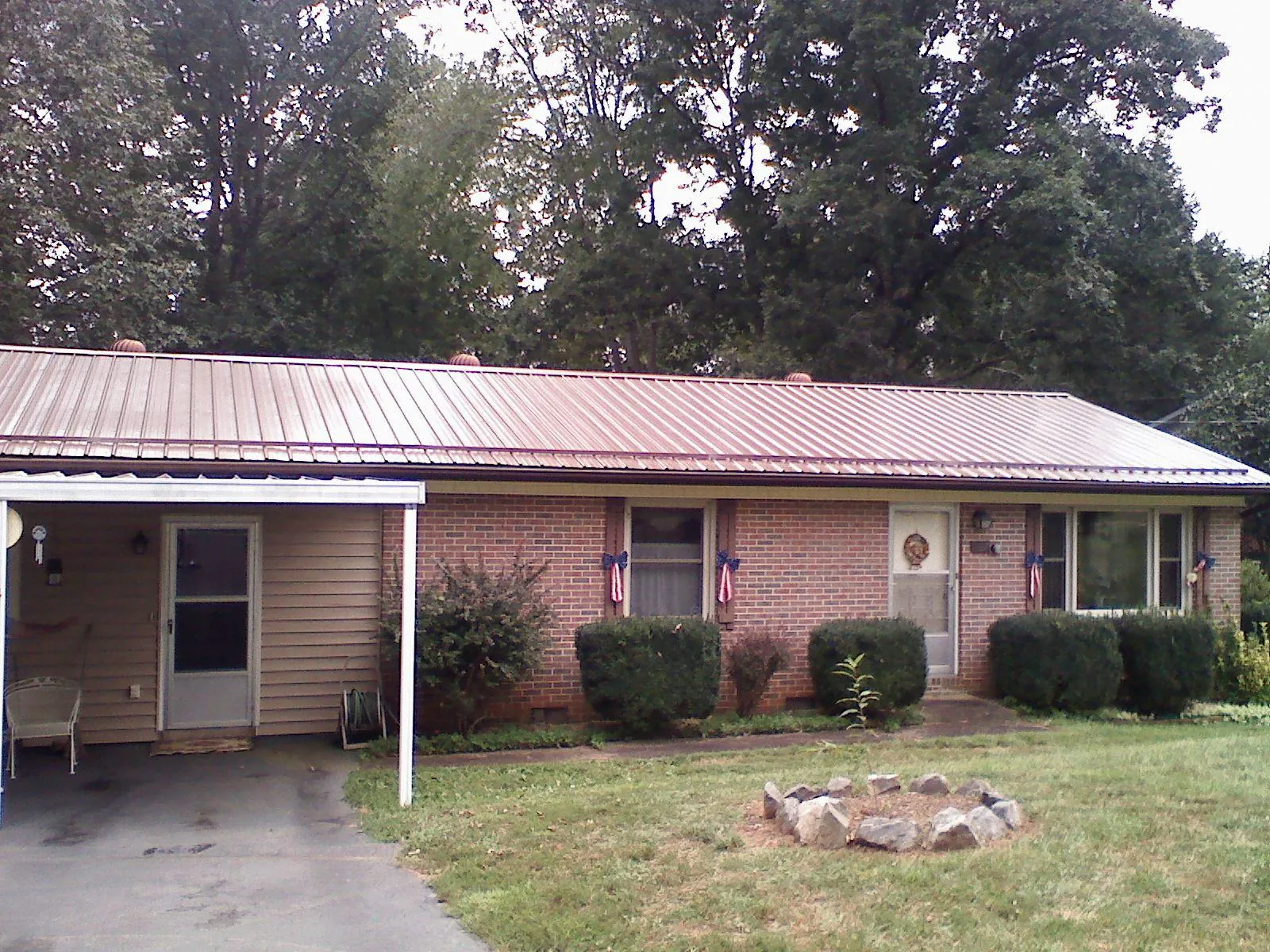 Bronze metal roof and carport on a brick ranch home — Roof Repair work by our crew in Haskell