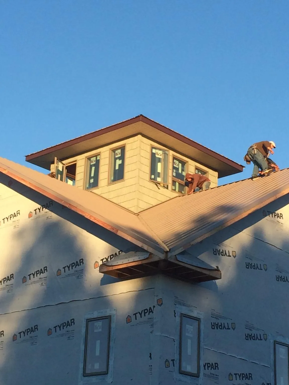 Roofers working around a rooftop cupola on a new metal roof at sunset — Roof Waterproofing in Haskell by Roofing Brothers